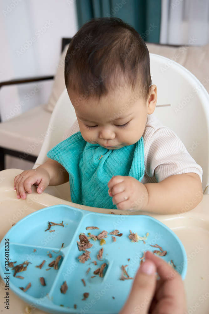 The baby is gathering food in the tray The baby is gathering food in the tray