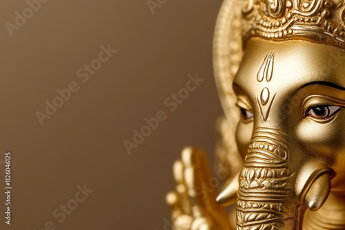 Golden ganesha idol close-up on brown background