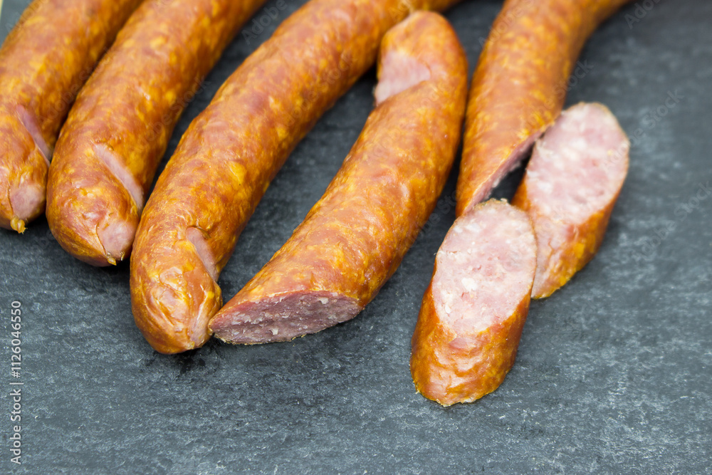The hunting sausages are on a black Cutting board. food preparation cutting. The hunting sausages are on a black Cutting board. food preparation cutting.