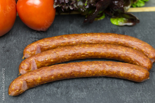 The hunting sausages are on a black Cutting board. food preparation cutting.