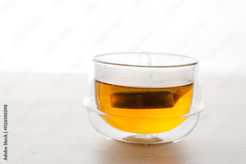 Cup of hot tea blended from rooibos, spearmint, apple, baobab on white wooden table.