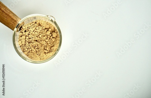 Green coffee powder food ingredients in small glassware cup pot isolated on horizontal copy spaced white background.