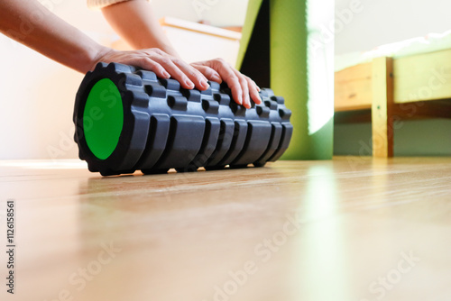 Close-up of hands holding a black massage roller in a home interior photo