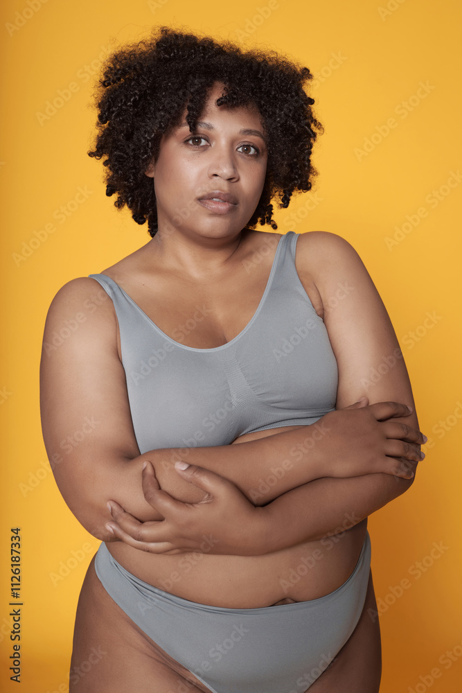 Portrait of African American body positive girl in underwear on yellow background Portrait of African American body positive girl in underwear on yellow background