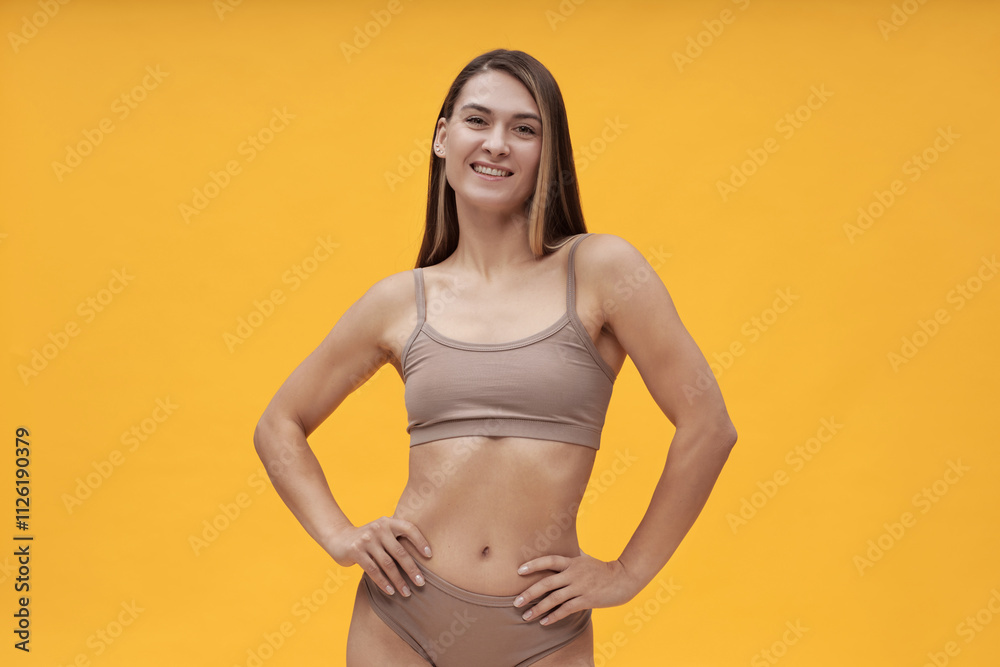 Fototapeta premium Portrait of beautiful young woman posing at camera against yellow background