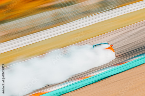 Dynamic panning shot of a drifting car on a racing circuit, surrounded by thick smoke from its burning tires, partially obscuring the vehicle. The motion blur emphasizes speed and adrenaline