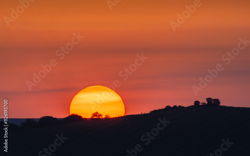 Wallpaper Mural Sunset behind a hill. Orange sky with yellow sun and silhouettes  in nature Torontodigital.ca