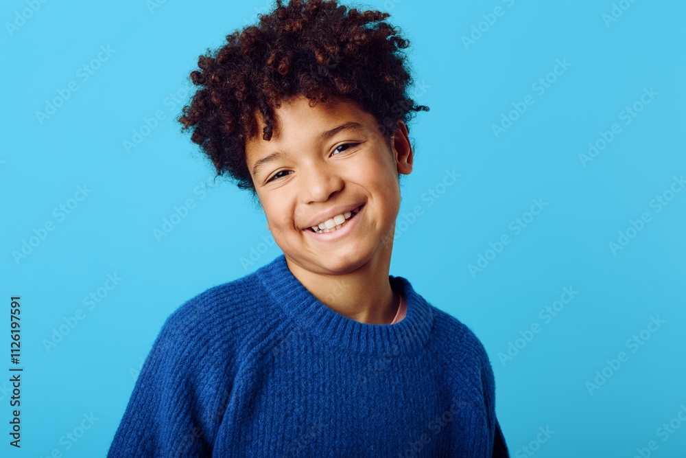 Joyful young african american boy with curly hair beaming against a vibrant blue backdrop, radiating happiness and charm Joyful young african american boy with curly hair beaming against a vibrant blue backdrop, radiating happiness and charm