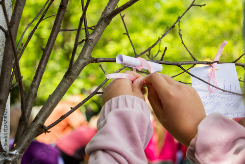 child attaches a note with wishes to a wishing tree, creativity, a holiday, a master class, a park, a garden, a walk