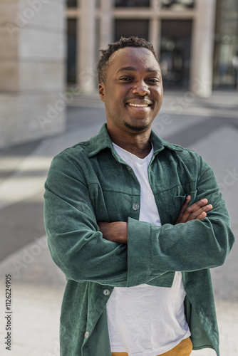 Cheerful African American young man standing near urban building photo