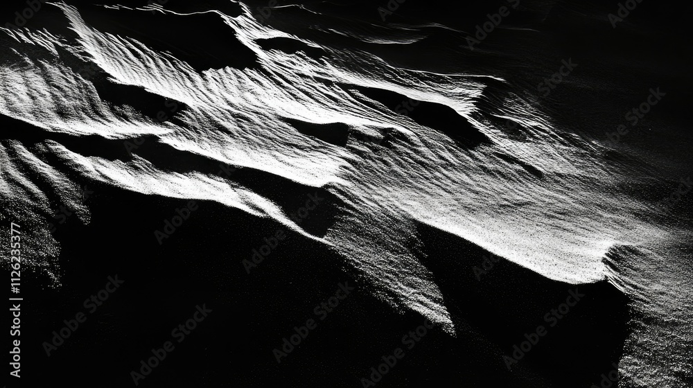 Obraz premium Close-up of small dunes and ridges on dry beach sand, highlighted by sharp sunlight and shadows