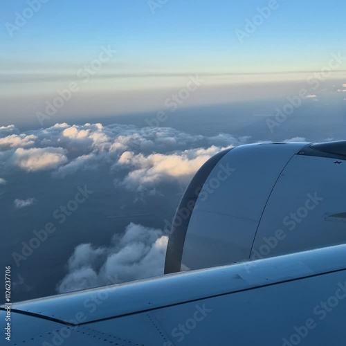 View from the airplane window at a beautiful cloudy sky and the airplane wing. Earth and sky as seen through window of an airplane.