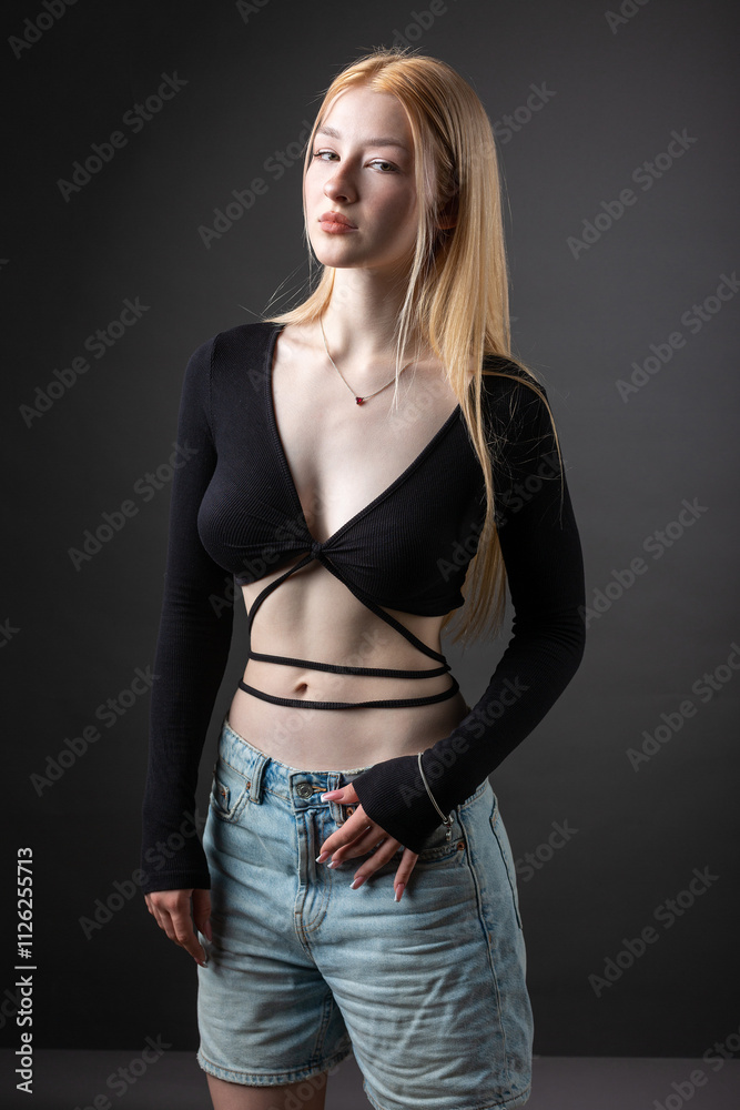 Portrait of a blonde woman with freckles in a sexy top and denim shorts in a studio. Portrait of a blonde woman with freckles in a sexy top and denim shorts in a studio.