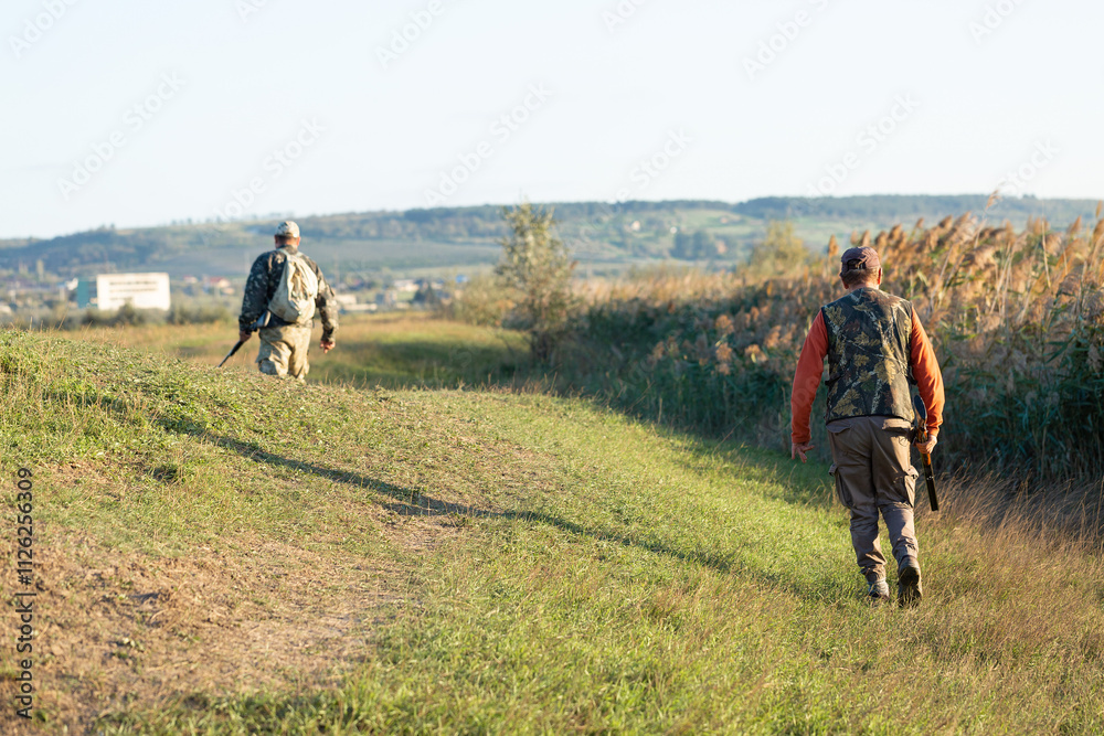 Mature hunter man holding a shotgun and walking through a field Mature hunter man holding a shotgun and walking through a field