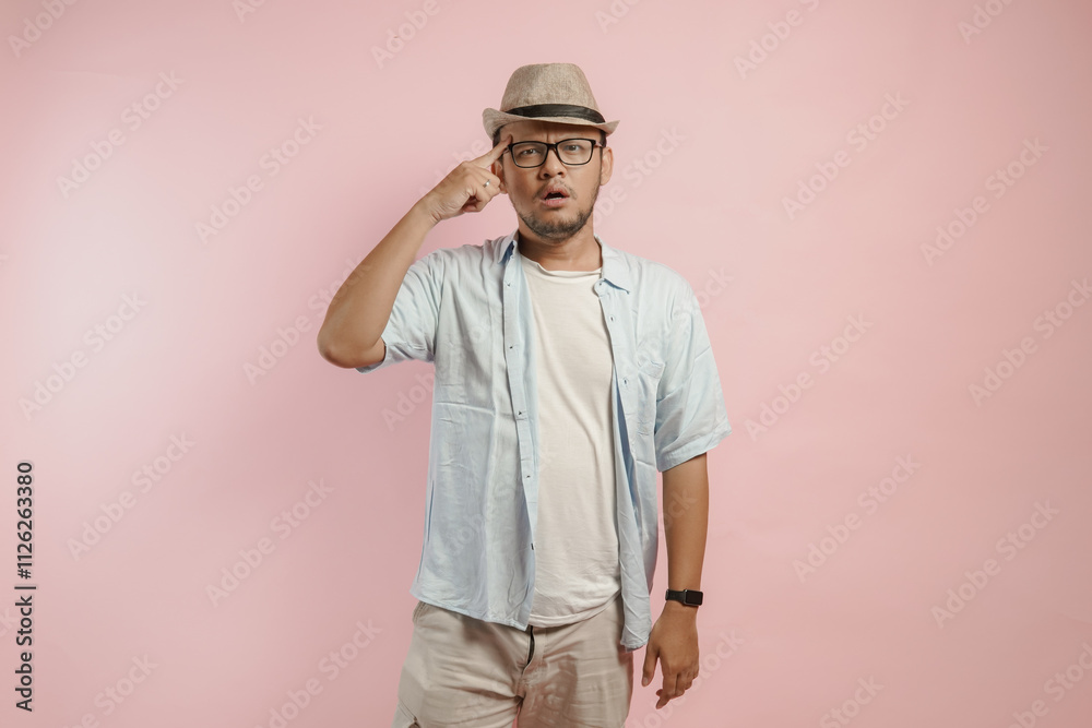 Thoughtful young Asian man wearing blue shirt and hat thinking of an idea with serious expression. Thoughtful young Asian man wearing blue shirt and hat thinking of an idea with serious expression.