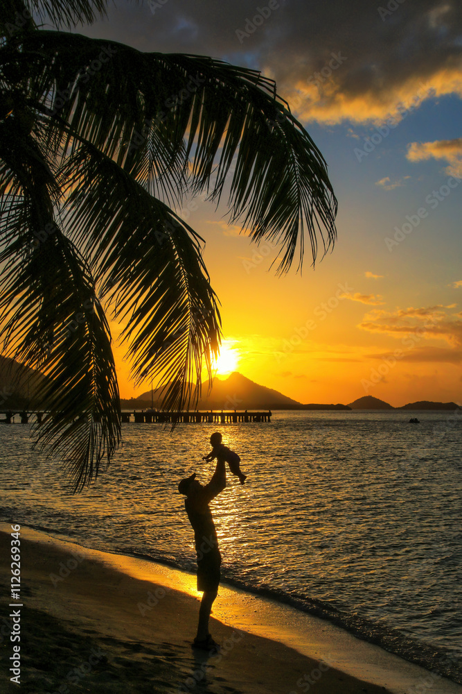 Φωτογραφία Man holding a baby in the air at sunset, Hillsborough Bay, Carriacou Island, Grenada