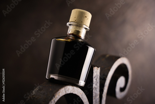 Bottiglietta di aceto balsamico, condimento tipico di Modena, isolata su fondo scuro, primo piano photo
