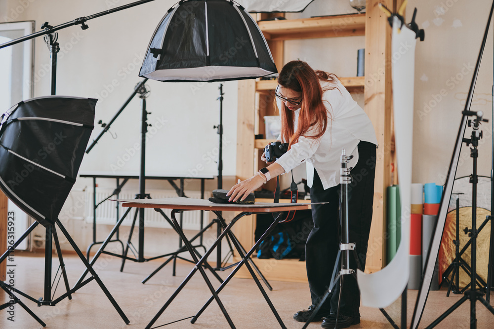 Female photographer taking photo of objects on background in photo studio with professional equipment Female photographer taking photo of objects on background in photo studio with professional equipment