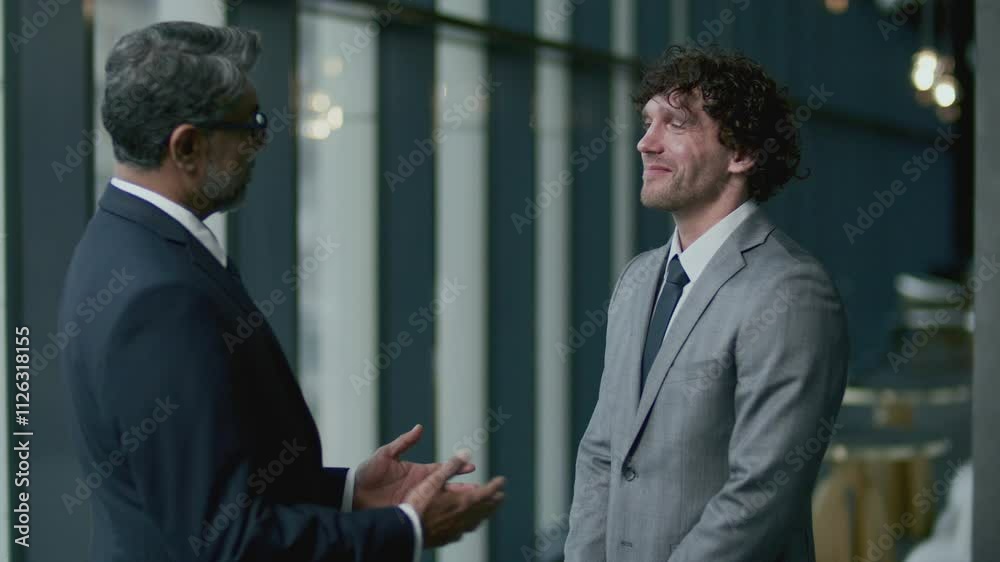 Businessman smiling, talking and shaking hands with senior partner after finalizing deal at meeting in restaurant Businessman smiling, talking and shaking hands with senior partner after finalizing deal at meeting in restaurant