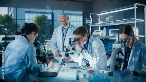 Obraz na plátně Young Team of Science Researchers Sitting Behind a Table, Using Microscopes for Medical Pharmaceutical Research and Treatment Development