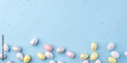 Festive Easter background. Multicolored Easter eggs on a blue table. Banner with a place for text. Top view. photo