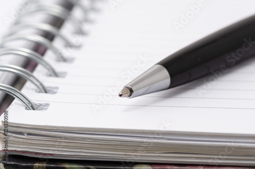 A pen is sitting on a spiral bound notebook