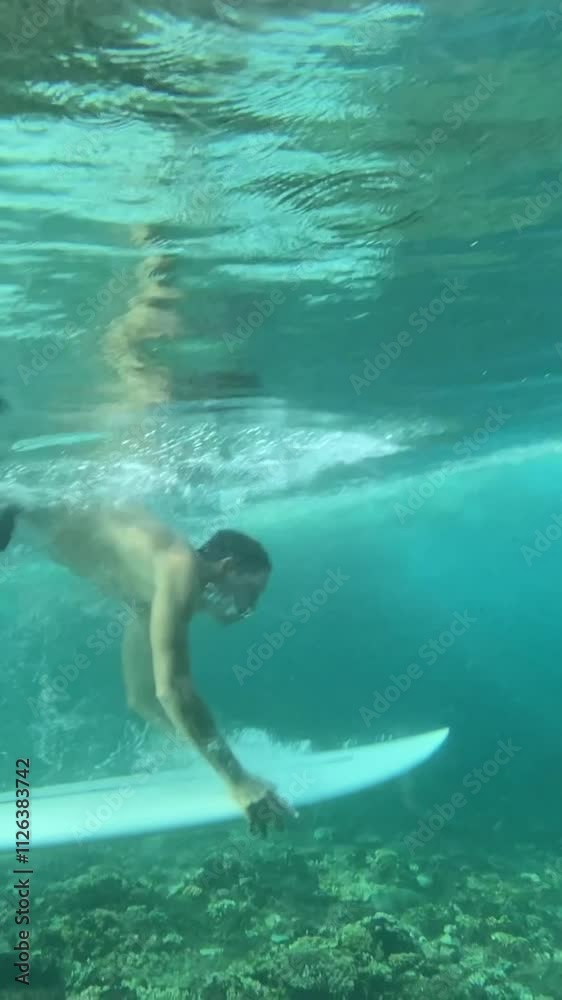 Young male surfer making duck dive in the ocean, Indonesia Young male surfer making duck dive in the ocean, Indonesia