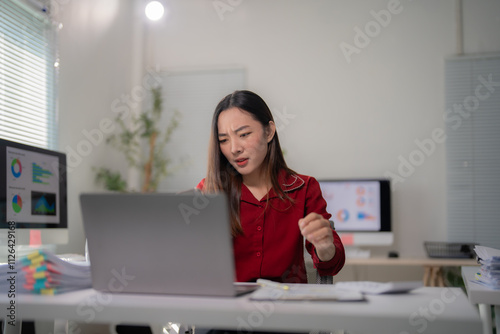 Young frustrated business woman feeling stressed and tired from work sitting at office desk with laptop and financial documents, having problem with project, overworked and deadline concept