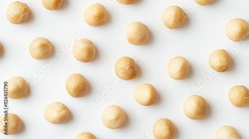 Macadamia nuts arranged in a uniform pattern on a clean white background showcasing their natural texture and color.