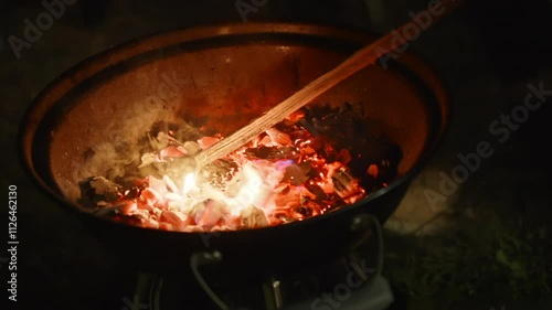 Stoking barbecue fire outdoor at night photo