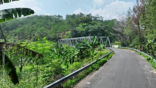 Video of B60 type steel truss bridge replacing the old collapsed bridge next to it over a clear river with stunning natural scenery photo