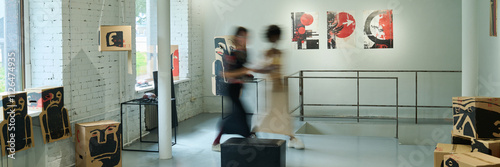 Slika na platnu Banner of blurry motion of two female visitors of art gallery walking along spac