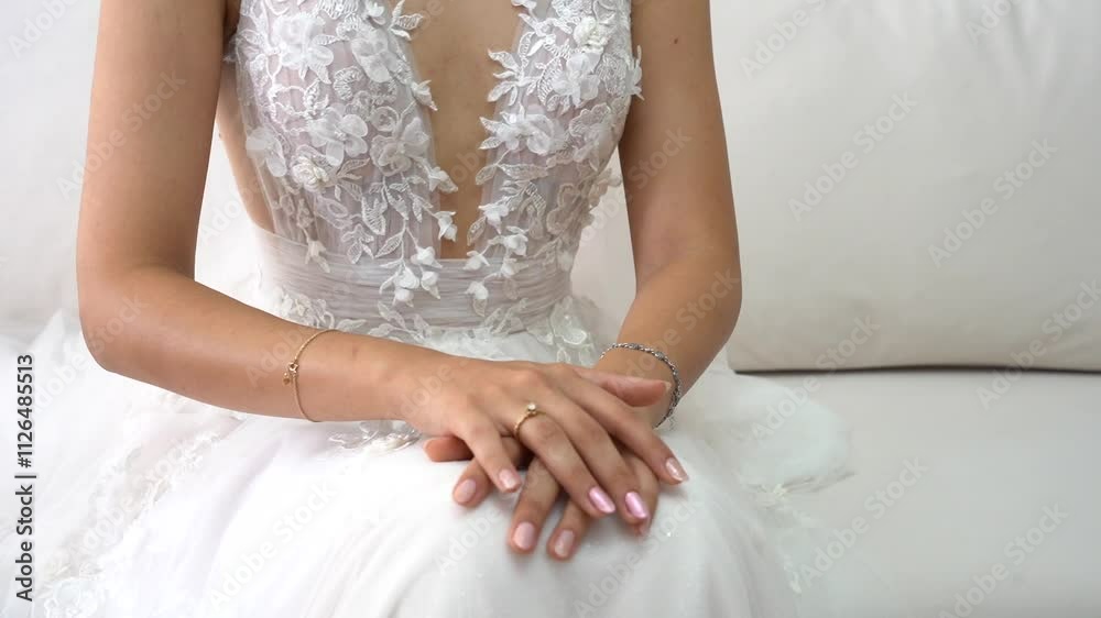 Elegant Bride in a Stunning Floral Lace Wedding Gown Sitting Gracefully on a White Sofa, Highlighting Sophisticated Jewelry and Perfectly Polished Nails for a Timeless Bridal Look Elegant Bride in a Stunning Floral Lace Wedding Gown Sitting Gracefully on a White Sofa, Highlighting Sophisticated Jewelry and Perfectly Polished Nails for a Timeless Bridal Look