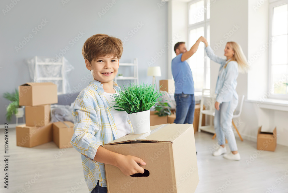 Portrait of smiling boy standing and holding cardboard box and plant in his hands with his parents having fun and dancing on background. Happy family moving new house, celebrating relocation together. Portrait of smiling boy standing and holding cardboard box and plant in his hands with his parents having fun and dancing on background. Happy family moving new house, celebrating relocation together.