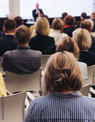 Female audience at the symposyum meeting, participants attendees in conference room hall listens to lecturer, group of women on a congress together listen to speaker on a stage at master-class