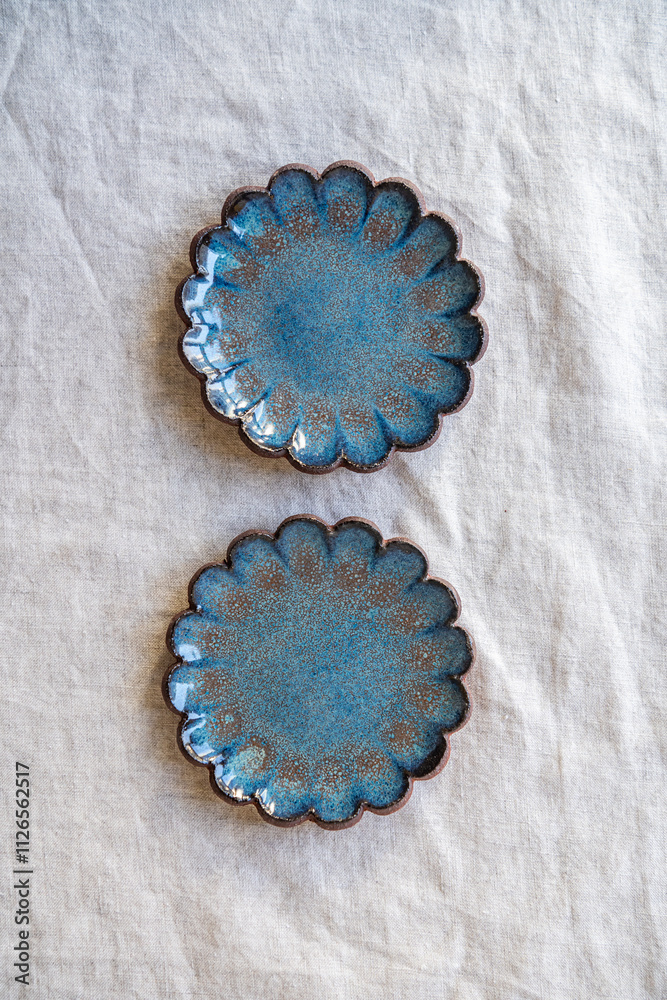 A selection of handmade stoneware ceramics in various glazes and decorations on a soft cloth background and setup A selection of handmade stoneware ceramics in various glazes and decorations on a soft cloth background and setup