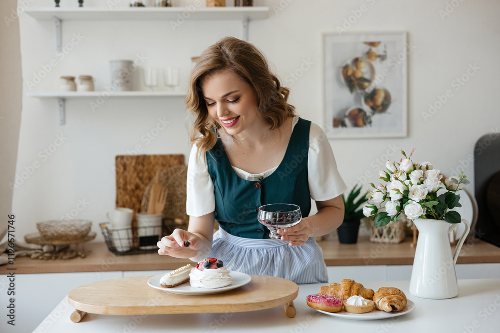 Beautiful girl adds a berry to the cake in the kitchen Beautiful girl adds a berry to the cake in the kitchen