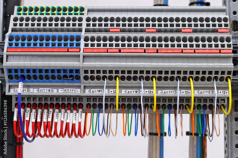 Fototapeta premium Electrical screw through terminals with connected insulated wires in an electrical switchboard.