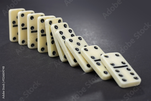 Fotografía Domino effect concept with white dominoes pieces row falling on dark background