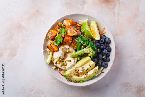 Balanced vegan bowl with baked sweet potato, avocado, berries, salad and hummus. Plant Based Diet Concept.
