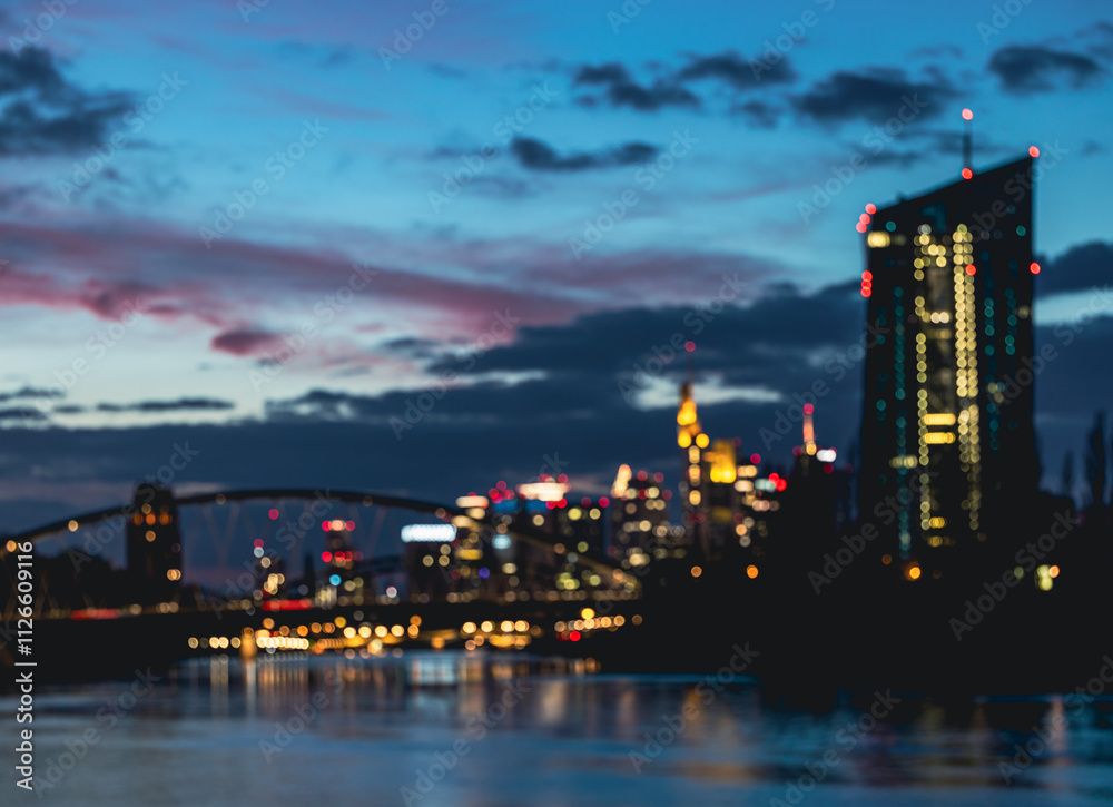 Naklejka premium Blurred Frankfurt skyline at dusk with illuminated city lights