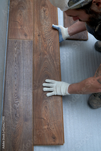 Men's gloved hands lay laminate flooring. view from above. the concept of repair and renovation. photo