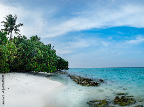 White sand sea beach panorama scenery with hot summer day in beautiful tropical paradise. Calm panoramic coastline landscape with exotic green trees and blue water waves, lagoon and clouds in sky