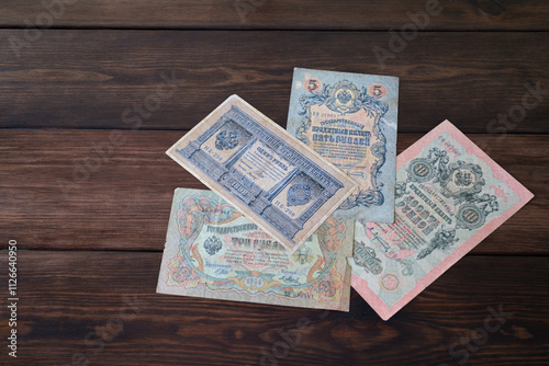 Vintage Russian Empire Banknotes with Denominations of 1, 3, 5, and 10 Rubles on Wooden Background photo