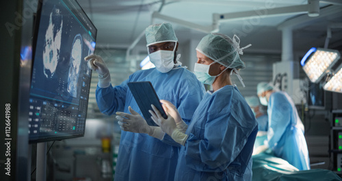 Black Male and Caucasian Female Surgeons Analyze Brain Scans on a Digital Monitor, Planning Surgical Strategy in a High-tech Operating Room. Colleagues Working Together, Preparing for Surgery