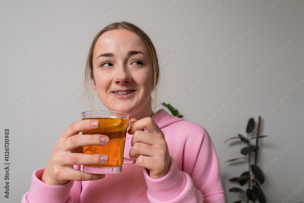 Young girl with braces holds cup with tea at the kitchen Young girl with braces holds cup with tea at the kitchen