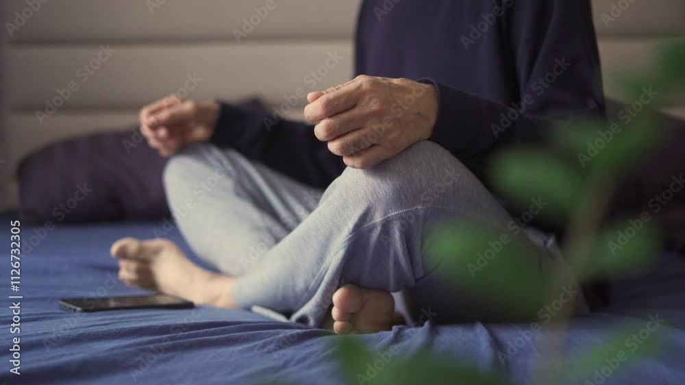 A man sits on a bed and meditates, focusing on breathing. A man sits on a bed and meditates, focusing on breathing.