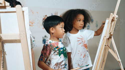 Happy creative african girl painted or draw canvas together with asian boy. Group of playful student create funny painting or artwork painted by watercolor. Creativity activity concept. Erudition. photo