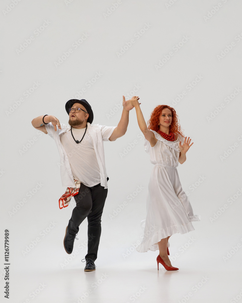 Obraz premium Passionate salsa duo perfects their dance moves, against white studio background, focusing on rhythm and coordination. Concept of dance class, music, lifestyle, hobby, art, dance school, talent.