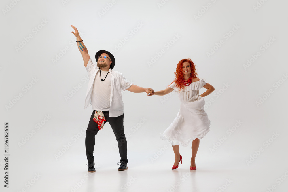 Naklejka premium In vibrant salsa training session, couple of dancers synchronize their movements against white studio background. In rhythm of love. Concept of dance class, hobby, art, dance school, talent